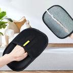 The black pet grooming glove in use in a living room, with a cat in the background